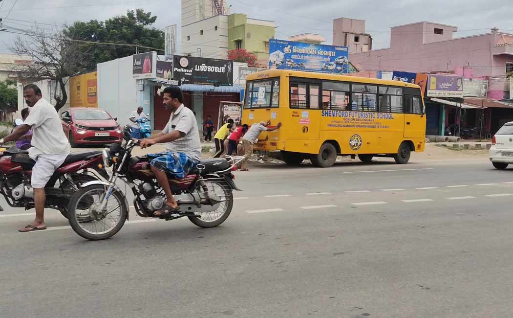 Students pushing a broken-down private school vehicle