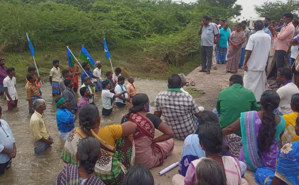 Villagers standing in flood waters demanding construction of a bridge