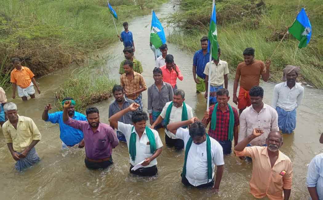 Villagers standing in flood waters demanding construction of a bridge